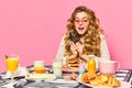 Bright emotional girl wearing pink sunglasses holding cutlery and looking at food with exciting face over pink