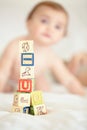 Start building on your childs future today. A tower of building blocks in the foreground with a cute baby sitting in the Royalty Free Stock Photo