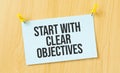 start with clear Objectives sign written on sticky note pinned on wooden wall