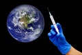 Start of covid-19 vaccination. Female hand in blue medical glove with syringe giving vaccine injection to planet Earth Royalty Free Stock Photo