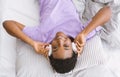 Start the day with music. Girl with wireless headphones lies in bed