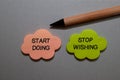 Start Doing or Stop Wishing write on sticky notes isolated on Office Desk