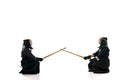 Start of fight. Two men, professional kendo athletes in uniform with helmet with bamboo shinai sword against white Royalty Free Stock Photo