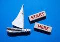 Start here symbol. Wooden blocks with words Start here Beautiful blue background with boat. Business and Start here concept. Copy Royalty Free Stock Photo