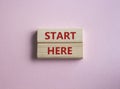 Start here symbol. Wooden blocks with words Start here Beautiful pink background. Business and Start here concept. Copy space Royalty Free Stock Photo