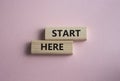 Start here symbol. Wooden blocks with words Start here Beautiful pink background. Business and Start here concept. Copy space Royalty Free Stock Photo