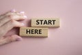 Start here symbol. Wooden blocks with words Start here Beautiful pink background. Businessman hand. Business and Start here Royalty Free Stock Photo