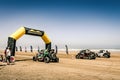 Start line of the Morocco Desert Challenge 2023. Rally raid side by side buggies driving over the beach of Plage Blanche.