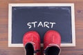 Start message and kid shoes on on chalkboard and wooden background. Royalty Free Stock Photo