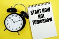 Start Now Not Tomorrow text with alarm clock flat lay on yellow background Royalty Free Stock Photo