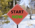 Start now symbol. Concept words Start now on beautiful red road sign. Beautiful forest snow blue sky background. Business Royalty Free Stock Photo
