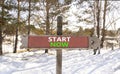 Start now symbol. Concept words Start now on beautiful wooden road sign. Beautiful forest snow blue sky background. Business Royalty Free Stock Photo