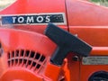 Start pull handle of old red Tomos-Husqvarna petrol chainsaw covered with some sawdust