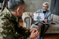 Start recovery. Mature psychologist holding picture with ink stain, Rorschach Inkblot in front of military man during