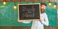 Start of school year concept. Teacher on cheerful face holds blackboard with title back to school. Man with beard