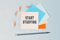 Start Studying - text on sticky note paper on gray background. Closeup of a personal agenda. Top view Royalty Free Stock Photo