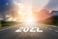 Start to New year 2022 concept. Start 2022 written on highway road in the middle of empty asphalt road with sunset or sunrise Royalty Free Stock Photo