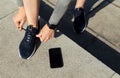 Start of training. Athlete tying shoelaces on sneakers, telephone on pavement near Royalty Free Stock Photo