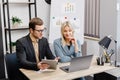 Start up business team on meeting in modern office interior, working on laptop and tablet. A young woman and a man are sitting at Royalty Free Stock Photo