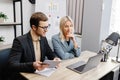 Start up business team on meeting in modern office interior, working on laptop and tablet. A young woman and a man are sitting at Royalty Free Stock Photo