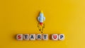 Start up concept. A symbol of a quick start of a new project in business. Rocket and cubes with text Start up on a yellow Royalty Free Stock Photo