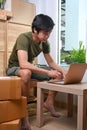 Start up small business owner sitting with cardboard box and working with laptop at home. Royalty Free Stock Photo