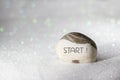 START word carved on stone on white sand with glittering