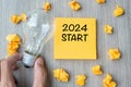 2024 Start words on yellow note and crumbled paper with Businessman holding lightbulb on wooden table background. New Year New Royalty Free Stock Photo