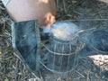 Experienced master bee keeper in his apiary setting a fire in a bee smoker.