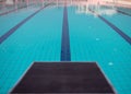 Starting blocks in row by the swimming pool, selective focus. Jump platform for swimming in swimming pool and grandstand backgroun Royalty Free Stock Photo