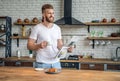 Starting day from good news. Handsome young man reading newspaper and smiling while drinking coffee and having breakfast in the Royalty Free Stock Photo