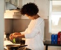 Starting the day with something scrumptious. a happy young woman cooking a fried egg at home.