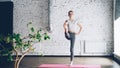 Starting female yoga student is doing sequence of balance exercises in one-to-one yoga class. She is sometimes awkward