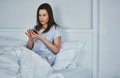 Starting her day with a quick text. an attractive young woman reading her text messages while lying in bed. Royalty Free Stock Photo