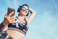 Starting her run training with music. Positive middle-aged beautiful woman jogging and listening to music using smartphone and Royalty Free Stock Photo