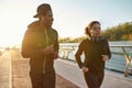 Starting new day from morning jog. Young african couple in sportswear jogging together on the bridge in the early Royalty Free Stock Photo