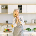 Thoughtful senior woman starting new day with coffee while standing in kitchen at home Royalty Free Stock Photo
