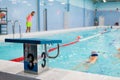 Starting platform with number three is in four lanes swimming pool for children groups. Kids do exercises with an instructor Royalty Free Stock Photo