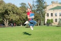 Starting school in good mood. Happy schoolgirl jump to music on green grass. Active little child in headphones hold