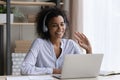 Confident biracial female in headset wave hand to laptop screen