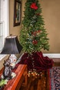 Starting to decorate the tree - Artificial Christmas tree with a few lights strung and others on wooden floor Royalty Free Stock Photo