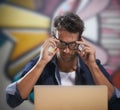 Starting your own business can be stressful...a thoughtful young entrepreneur adjusting his glasses while working at his