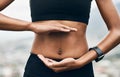 It starts from the inside. Closeup shot of a sporty unrecognizable woman holding her hands against her stomach outside. Royalty Free Stock Photo