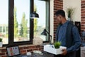 Startup employee getting fired holding tray with personal belongings giving a last look at his desk Royalty Free Stock Photo