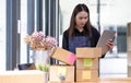 Startup happy Asian woman business owner works with a box at home, prepare parcel delivery SME supply chain, procurement, package