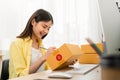 Startup small business concept, young woman owner working and packing on the box to customer at home office, seller prepares.