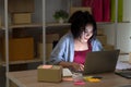 Startup small business entrepreneur young Asian woman small business owner sitting in fron of laptop on wooden table checking