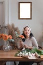 Startup, small business, flower shop. Older florist putting a flower on a vase