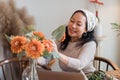 Startup, small business, flower shop. Older florist putting a flower on a vase