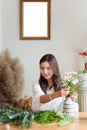 Startup, small business, flower shop. Young pretty florist putting a flower on a vase